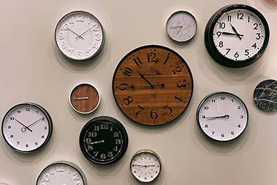 Une série d’horloges aux teintes marron, noire ou blanche sont fixées sur un mur pour illustrer l’ensemble des tâches quotidiennes des entrepreneuses et entrepreneurs.
