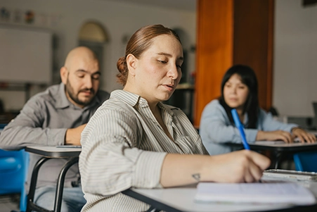 Trois personnes adultes suivent une formation professionnelle en salle et prennent des notes.<br />
